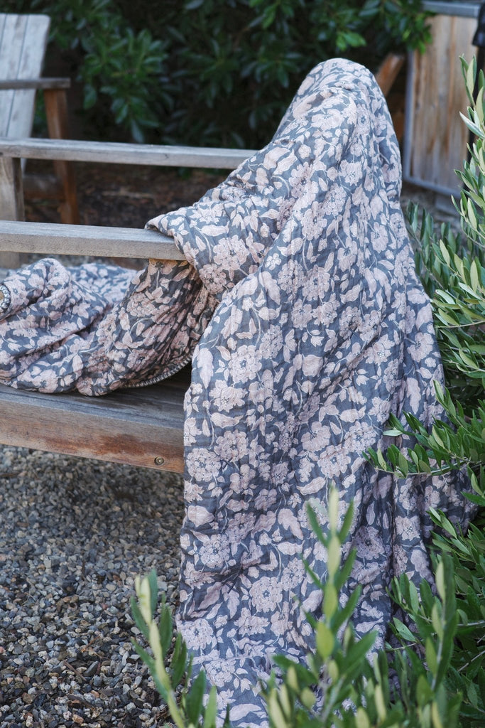 House no.23's Anthracite Flower Sherpa Cottage blanket with charcoal and lilac floral pattern draped outdoors, capturing its soft texture and cozy warmth in natural light. 