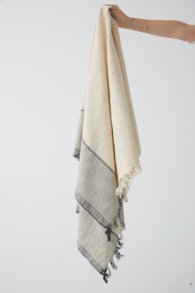 throw blanket with thin grey stripes on the edge , and hand knotted tassels on the edge